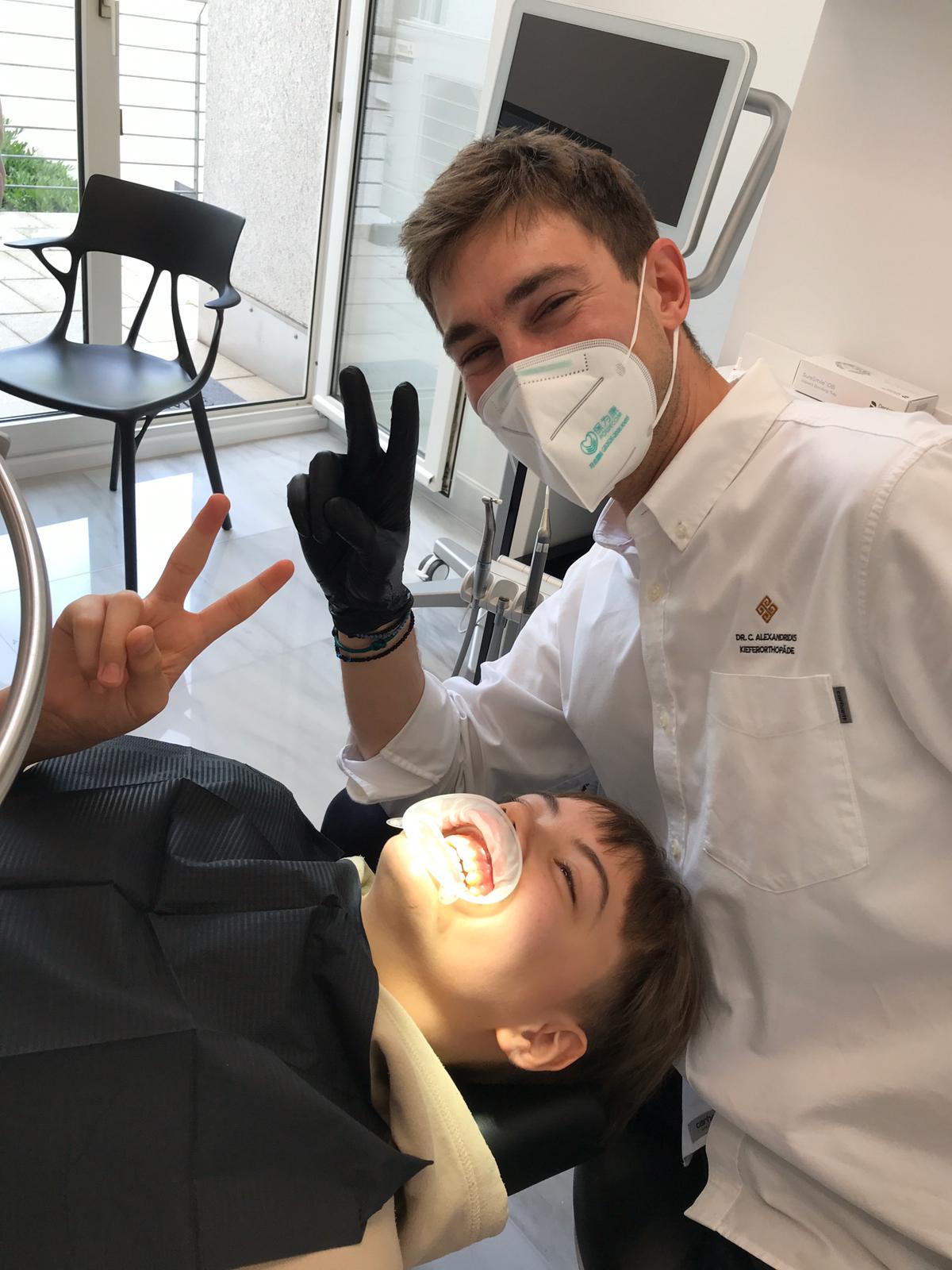 Dr. Alexandridis mit jungem Patient zeigt Peace in Kamera